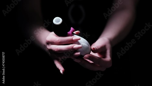 Vibrator in the shape of a penguin. Vacuum-wave clitoral stimulator in the hand of a girl on a black background. Sex Shop Products, Adult Gifts for Couples, Adult Store
 photo