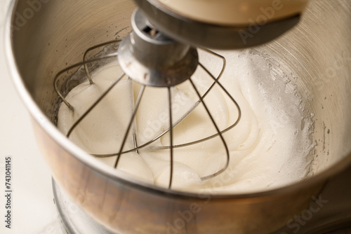 Whipped cream in a stand mixer with a whipping attachment