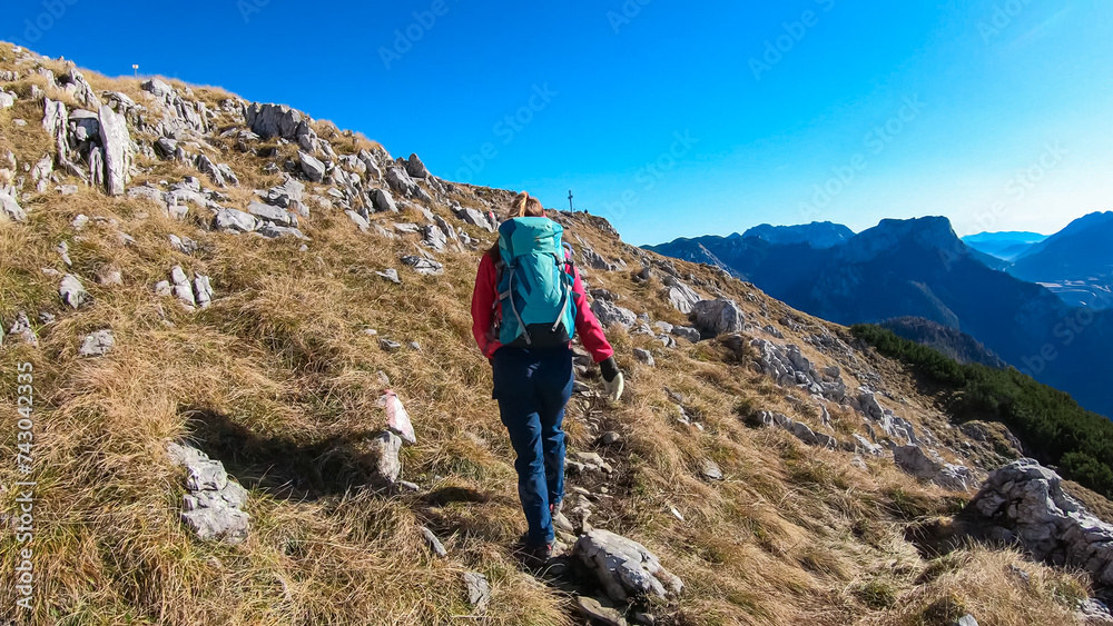 Hiker woman on idyllic hiking trail to mountain peak Hochblaser in Eisenerz, Ennstal Alps, Styria, Austria. Panoramic view of majestic alpine landscape in remote nature in summer. Wanderlust concept