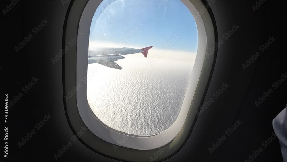 Aerial view through window of commercial airliner with blue sky and radiant sea Aerial view through window of commercial airliner with blue sky and radiant sea