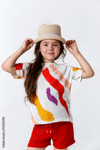 Portrait of cute kid girl model in straw hat arm touch standing on white background