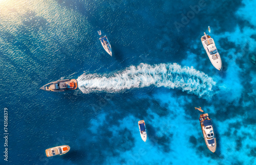 Aerial view of beautiful luxury yacht and boat in blue sea on summer sunny day. Sardinia island, Italy. Top drone view of speed boat, sea coast, transparent water. Travel. Tropical landscape. Yachting