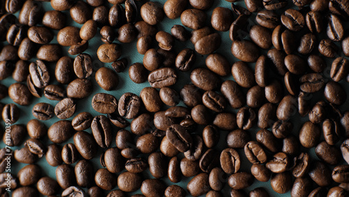 Background of coffee beans on a dark turquoise, cyan background. Close up