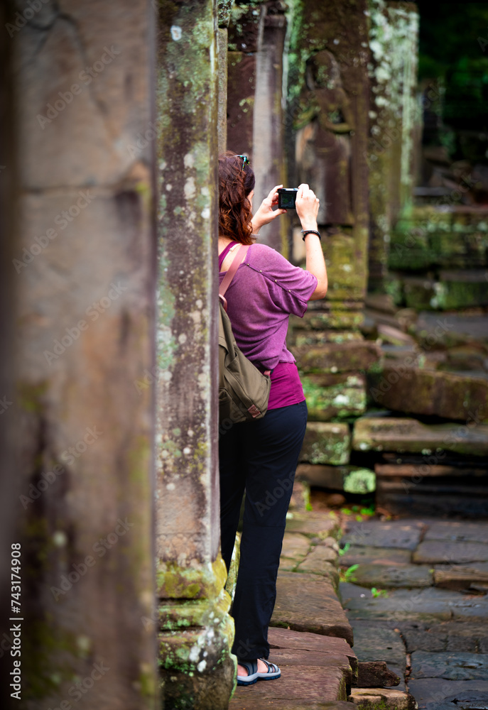 Tourist taking pictures in one of the corridors in an angkor thom temple in Cambodia Tourist taking pictures in one of the corridors in an angkor thom temple in Cambodia
