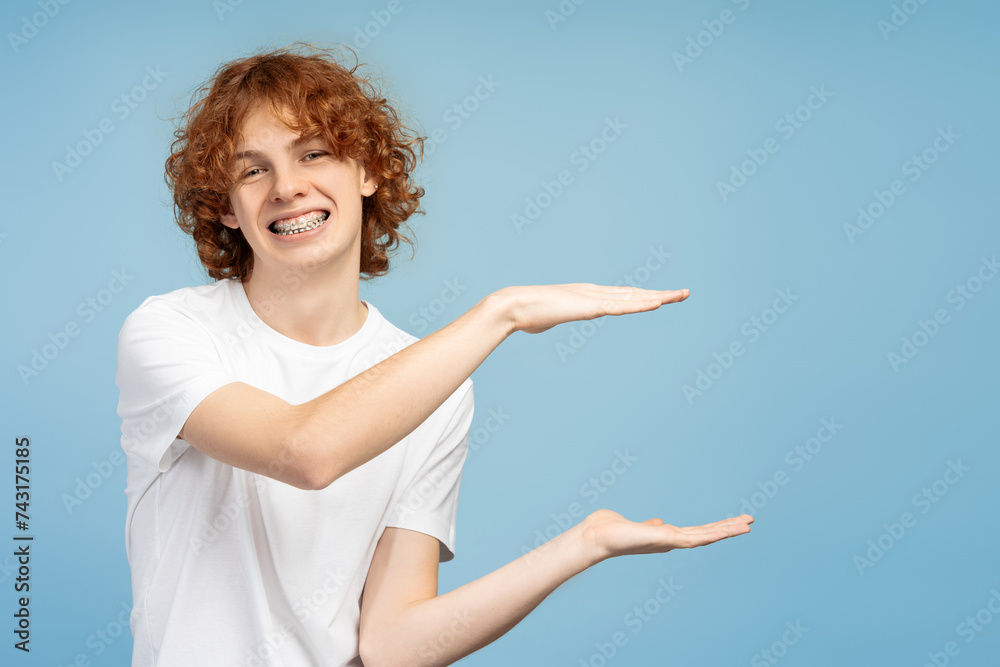 Smiling curly haired redhead teenage boy with braces, making a frame with his hands for text Smiling curly haired redhead teenage boy with braces, making a frame with his hands for text