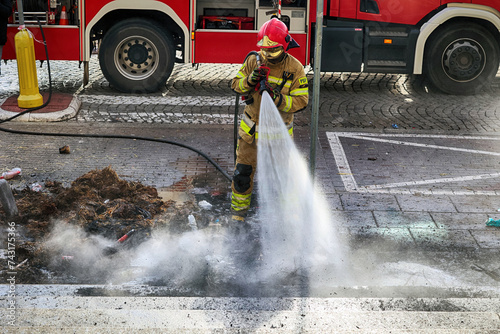 Strażak w kłębach dymu gasi pożar.
