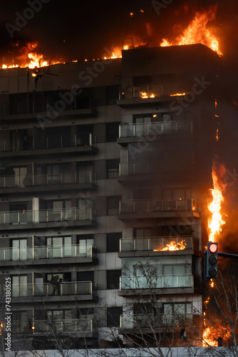 Large fire in a residential building in the city of Valencia, Spain, burning rapidly with firefighters on the second floor trying to escape the flames photo