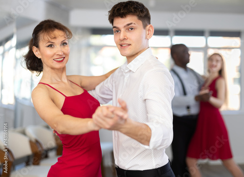 Young man and adult woman dance couple tango dance in studio