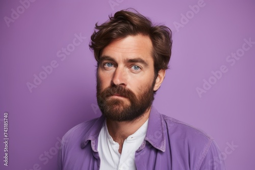 Portrait of a handsome young man with a beard on a violet background © Igor