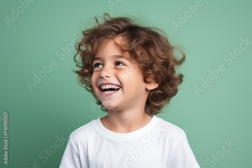 Portrait of a happy little boy with curly hair over green background