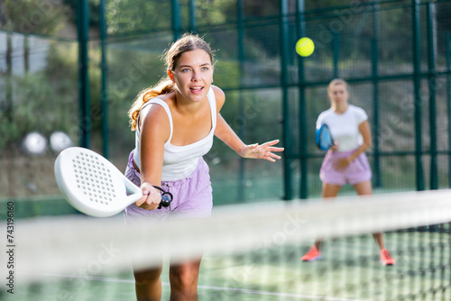 Woman padel tennis player training on court. Woman using racket to hit ball. © JackF