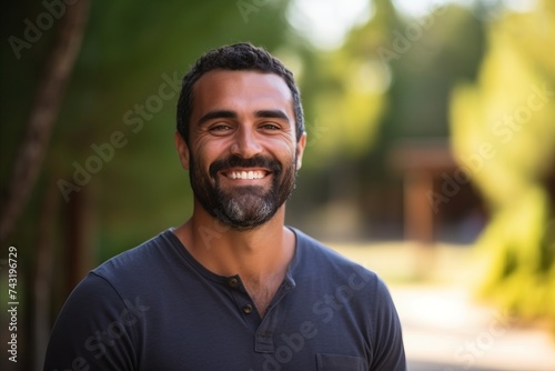 Portrait of a handsome bearded Indian man smiling at the camera outdoors