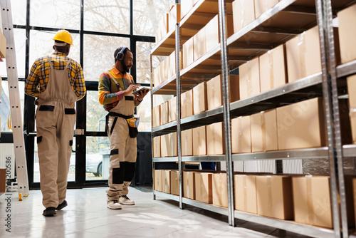African american warehouse employee in headphones overseeing parcels security and maintenance. Post office shipment operator listening to music and working in storage room