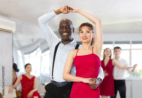 Couple of adult man and adult woman dancing waltz in studio