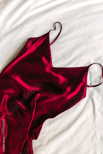 Red silk dress lying on the bed, overhead view photo