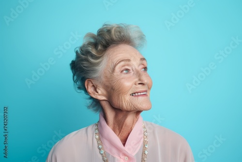 Portrait of a happy senior woman smiling at the camera on a blue background