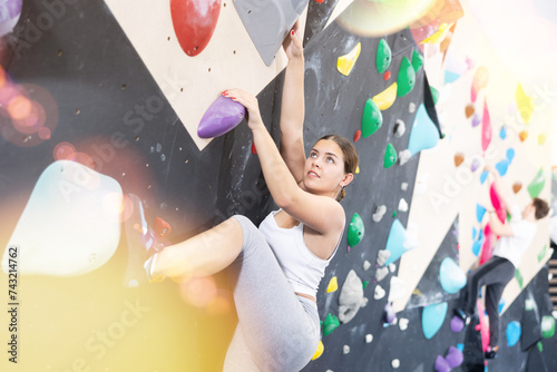 Young woman in sportswear practices rock climbing on climbing wall