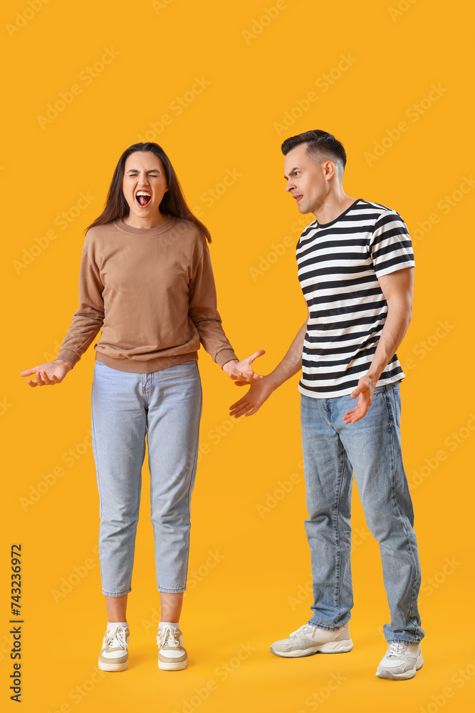 Young couple quarreling on yellow background