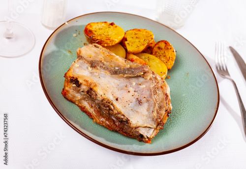 Roasted meaty pork ribs served on plate with fried golden baked potatoes.