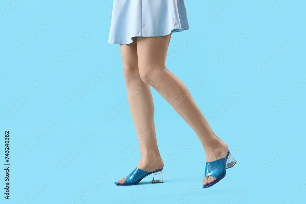 Legs of young woman in stylish blue sandals on color background Legs of young woman in stylish blue sandals on color background