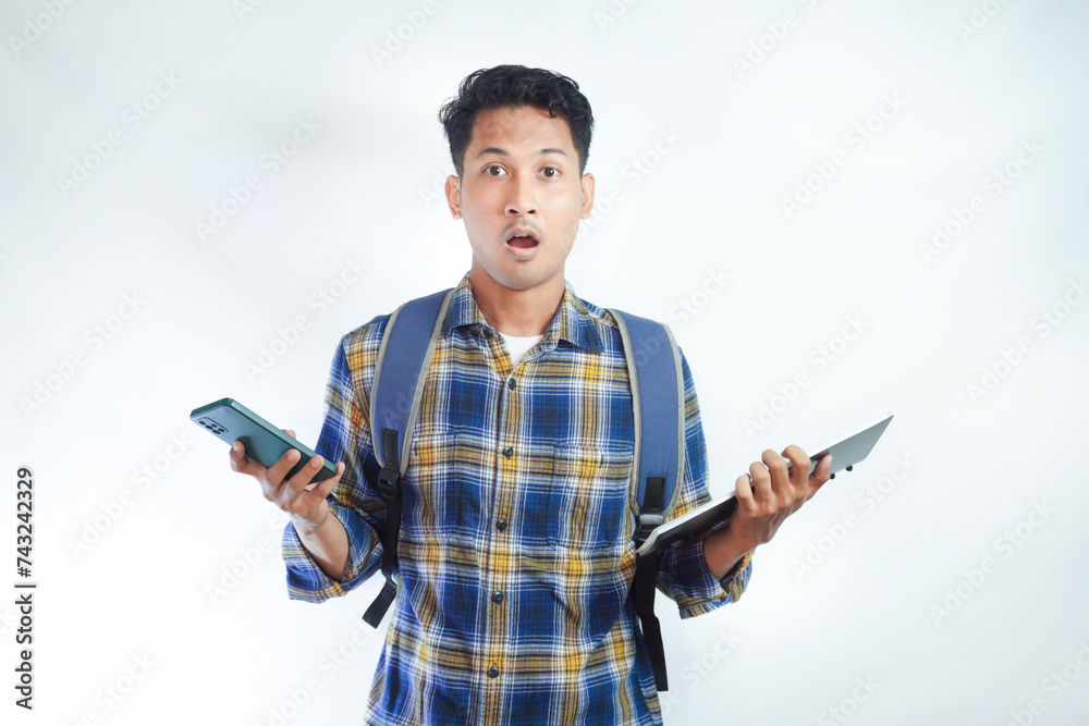 Surprised young Asian man student in casual clothes backpack glasses using mobile cell phone, chatting online and reading news isolated on white background. high school university college concept Surprised young Asian man student in casual clothes backpack glasses using mobile cell phone, chatting online and reading news isolated on white background. high school university college concept