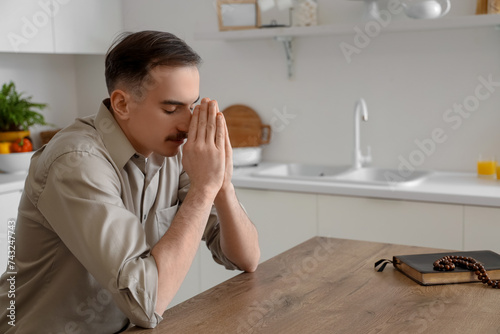 Young man praying at table ...