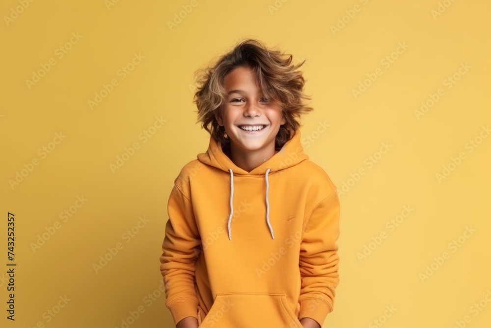 Portrait of a smiling little boy in a yellow hoodie over yellow background