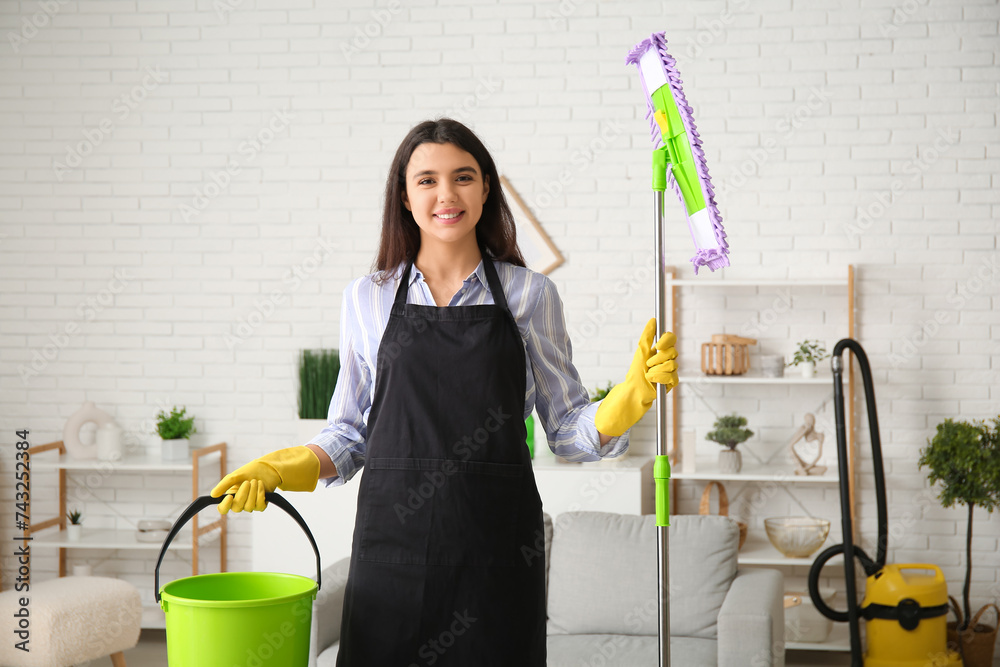 Young woman with floor mop and bucket in living room
