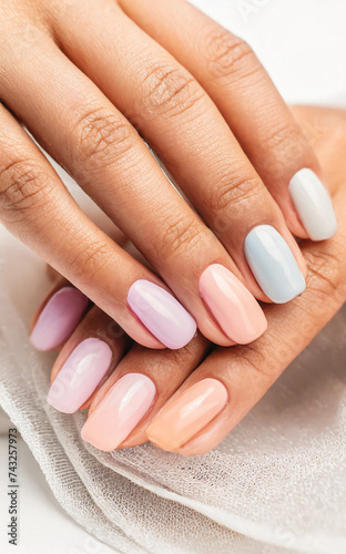 Close-up of woman's hands with elegant manicure of different bright and colorful colors. Beautiful nude manicure on long nails. Nail manicure with gel polish in a luxury beauty salon