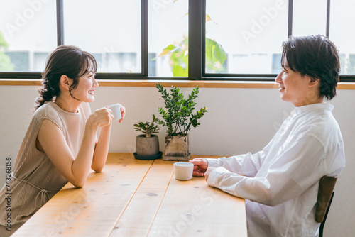 カフェ・家のダイニングで会話する仲良しの若い日本人夫婦 