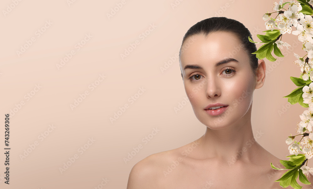Beautiful woman with smooth skin and flowers on beige background. Space for text Beautiful woman with smooth skin and flowers on beige background. Space for text
