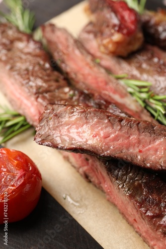 Delicious grilled beef with rosemary and tomato on table, closeup