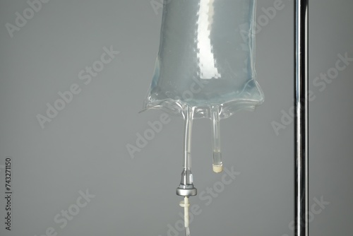 IV infusion set on pole against grey background, closeup. Space for text