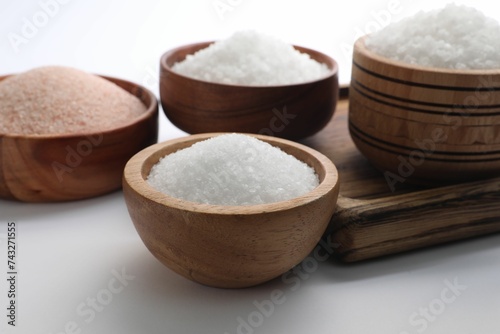 Different types of natural salt in wooden bowls on white background