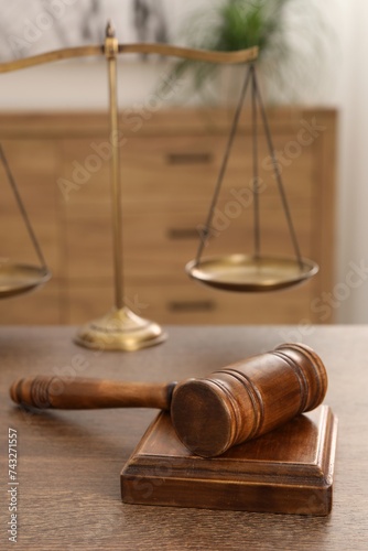 Wooden gavel, sound block and scales on table indoors