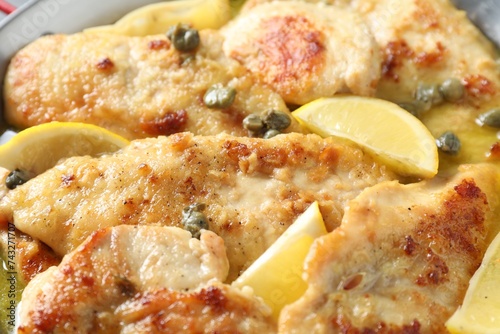Delicious chicken piccata with lemons as background, closeup
