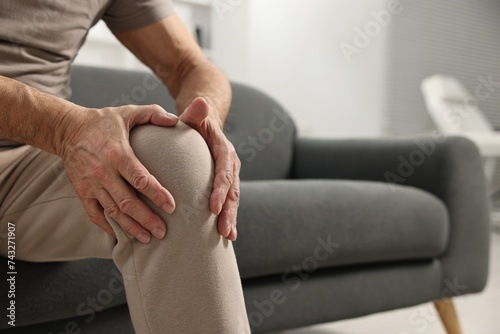Arthritis symptoms. Man suffering from pain in knee at home, closeup