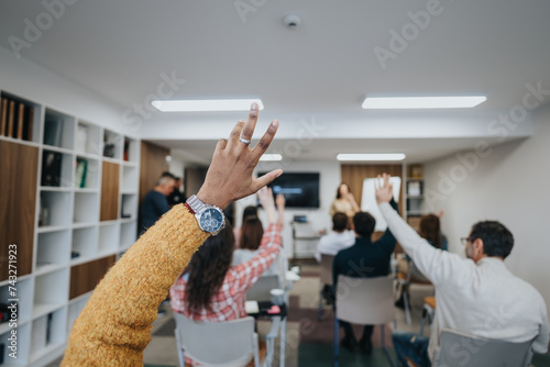 Focused group of people in a workshop setting with raised hands eager to ask questions or provide answers during an interactive session.