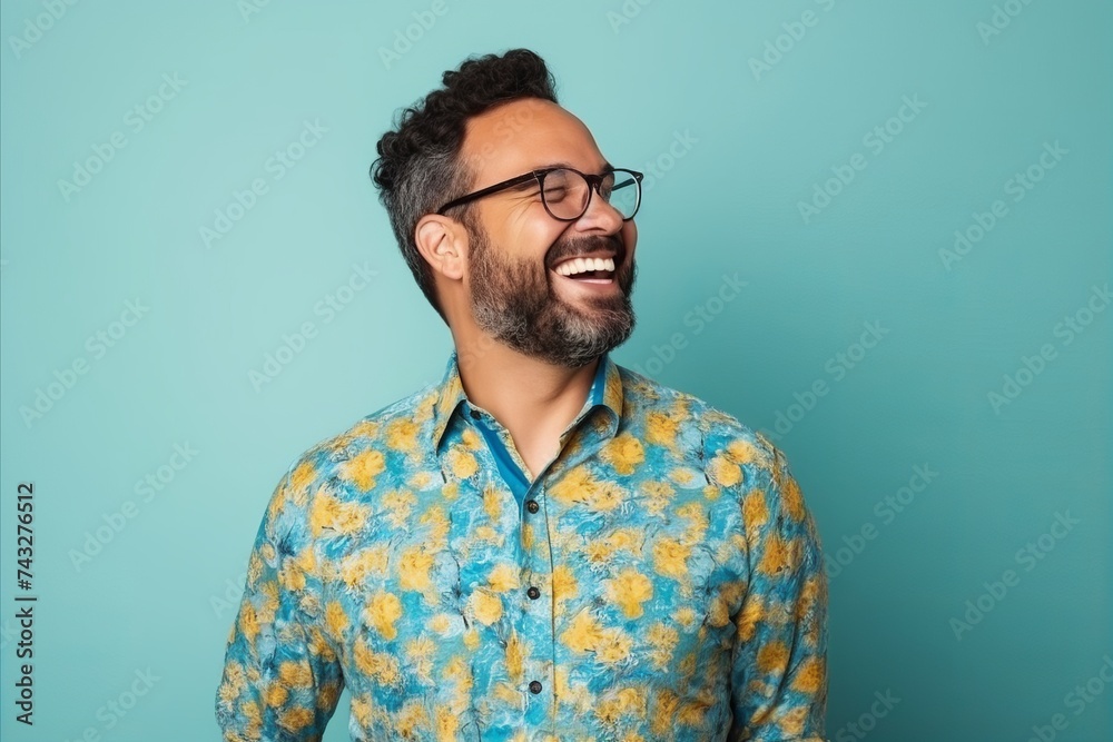 Young hipster man with beard and glasses laughing on a blue background Young hipster man with beard and glasses laughing on a blue background