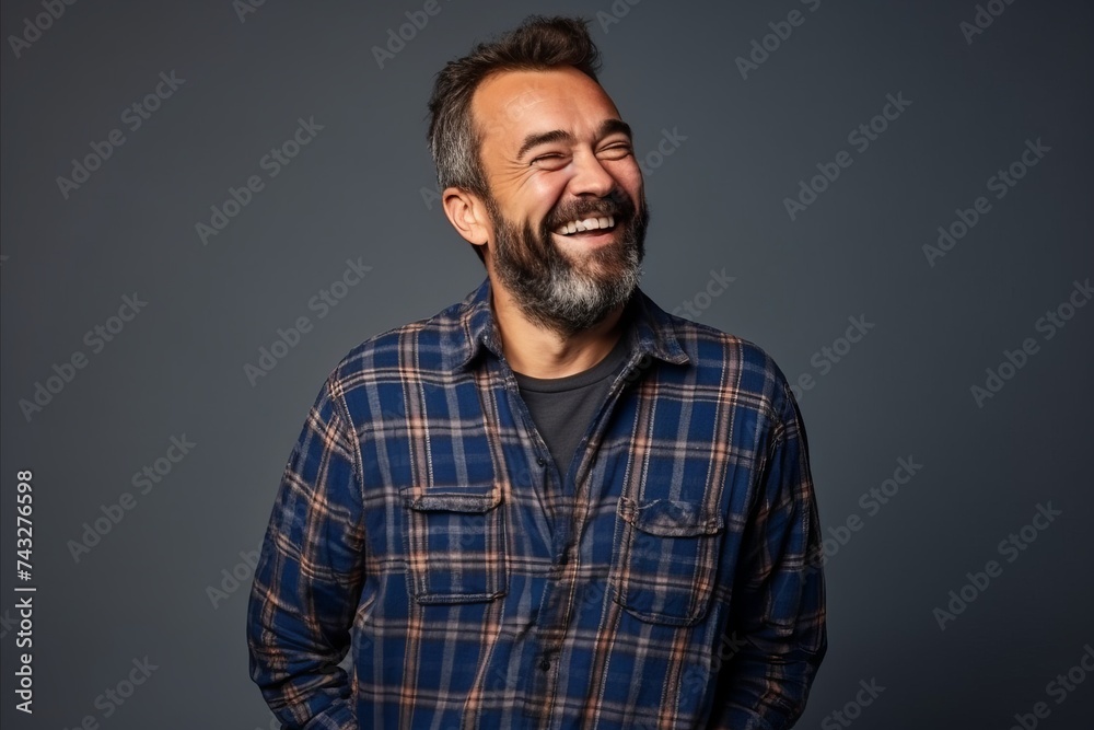 Portrait of a middle-aged man laughing over grey background.