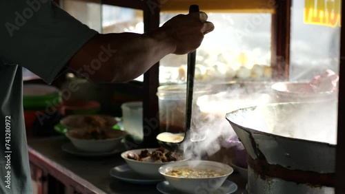 Prepare a bowl of Indonesian chicken soup or soto ayam. A vendor preparing fresh chicken soup (soto ayam) lamongan to the customers at Tarakan, Indonesia. Preparing soto ayam. Selective focus. photo
