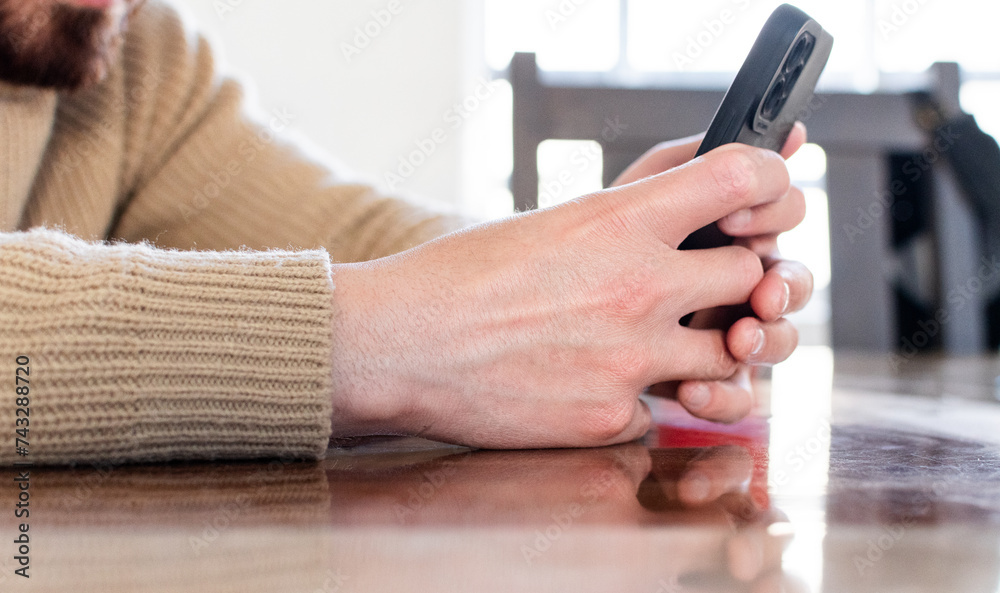 Close up de manos de hombre sosteniendo su teléfono celular y bebiendo café en casa. Recreación y tiempo libre 