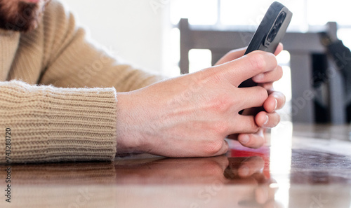 Close up de manos de hombre sosteniendo su tel  fono celular y bebiendo caf   en casa. Recreaci  n y tiempo libre 