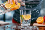 A refreshing citrus cocktail is expertly crafted with a splash of meyer lemon juice, key lime, grapefruit, and orange, all poured gracefully into a drinkware glass by a skilled hand