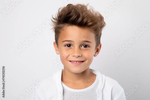 Portrait of a cute little boy with funny hairstyle over grey background