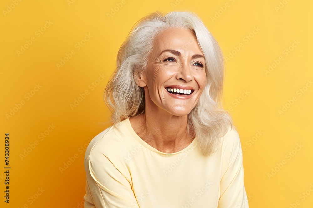 Beautiful senior woman smiling and looking at camera over yellow background. Beautiful senior woman smiling and looking at camera over yellow background.
