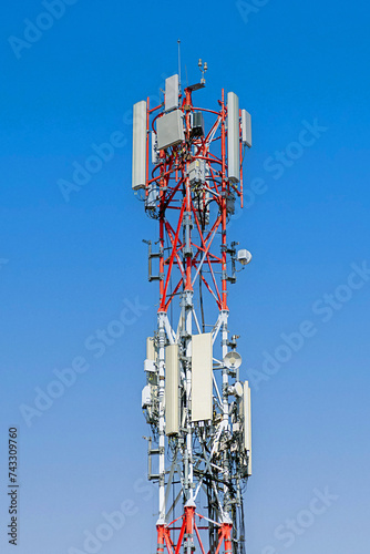 Tall cell tower antenna mast with blue sky in background