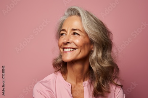 Portrait of happy mature woman looking at camera, isolated over pink background