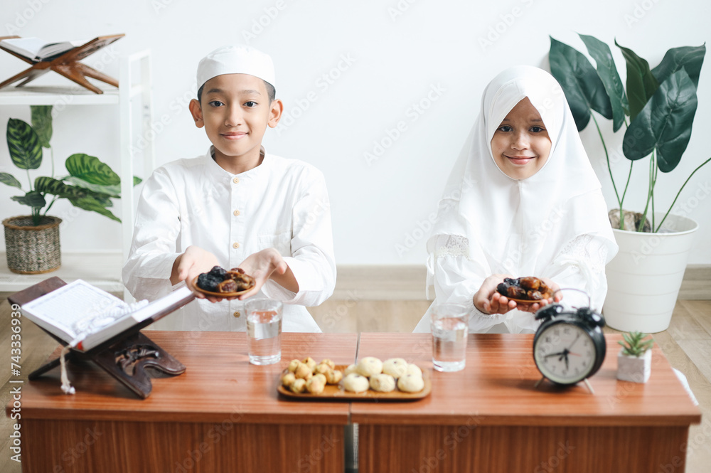 Asian muslim brother and young sister holding fruit dates on wooden tray on iftar time Asian muslim brother and young sister holding fruit dates on wooden tray on iftar time