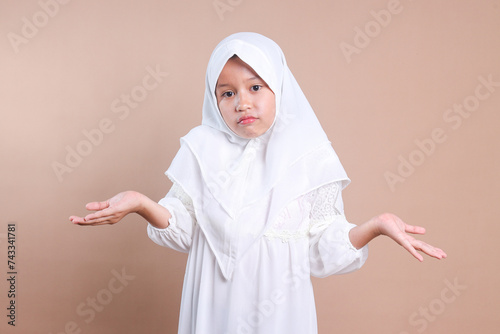 Photography Asian muslim little girl with hijab shrugging her shoulder showing don't know an